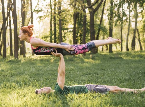 man-balancing-woman-his-while-practicing-yoga-park